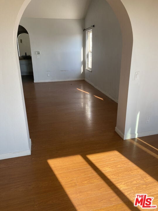 spare room featuring lofted ceiling and dark hardwood / wood-style floors