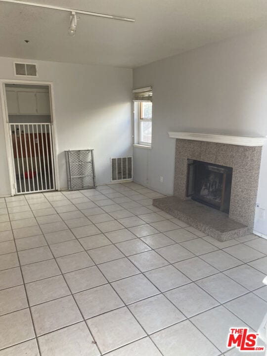 unfurnished living room featuring a tile fireplace and light tile patterned floors