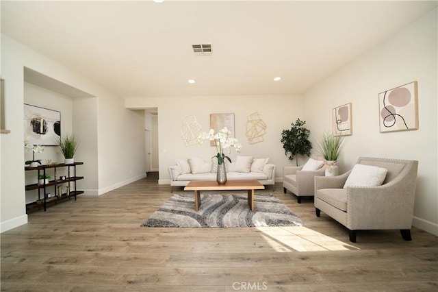 living room featuring baseboards, visible vents, wood finished floors, and recessed lighting