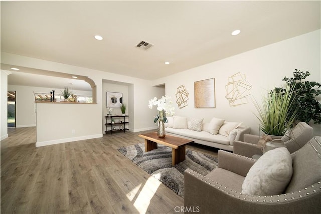 living area with baseboards, wood finished floors, visible vents, and recessed lighting