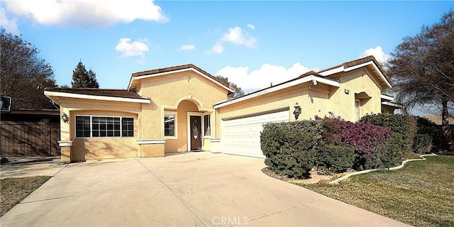 view of front facade with concrete driveway, an attached garage, and stucco siding