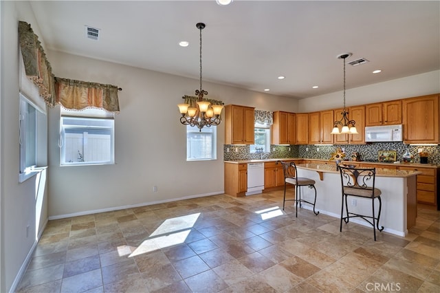 kitchen featuring a kitchen island, a notable chandelier, white appliances, and decorative light fixtures