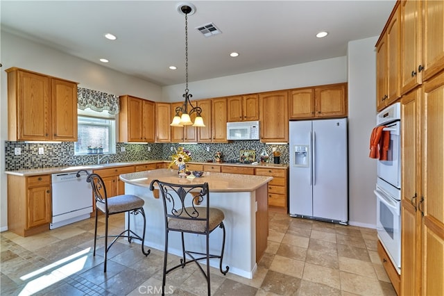 kitchen featuring a breakfast bar area, tasteful backsplash, a kitchen island, pendant lighting, and white appliances