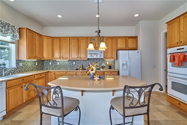 kitchen featuring pendant lighting, sink, white appliances, and a center island