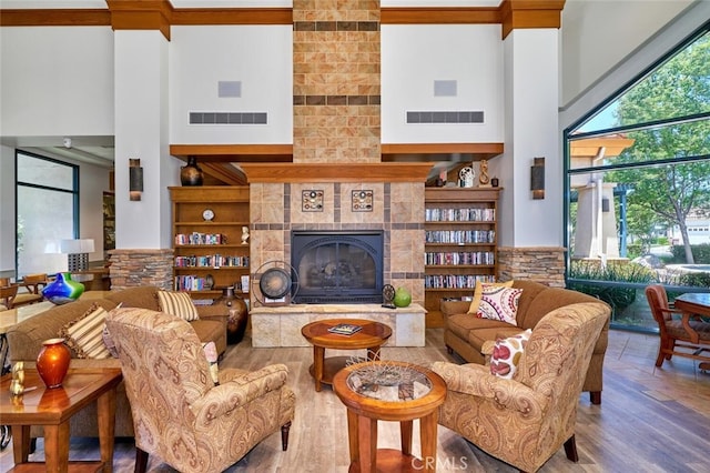 living room featuring hardwood / wood-style floors, a towering ceiling, and a tile fireplace