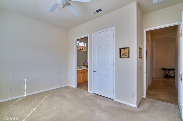 unfurnished bedroom with light carpet, ensuite bath, and ceiling fan