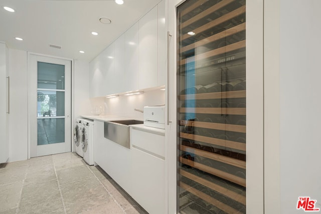 kitchen featuring wine cooler, washer and clothes dryer, white cabinets, and sink