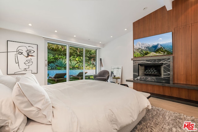 bedroom with access to exterior, vaulted ceiling, and light hardwood / wood-style flooring