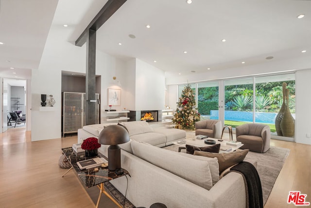 living room with light wood-type flooring, beam ceiling, and a high ceiling