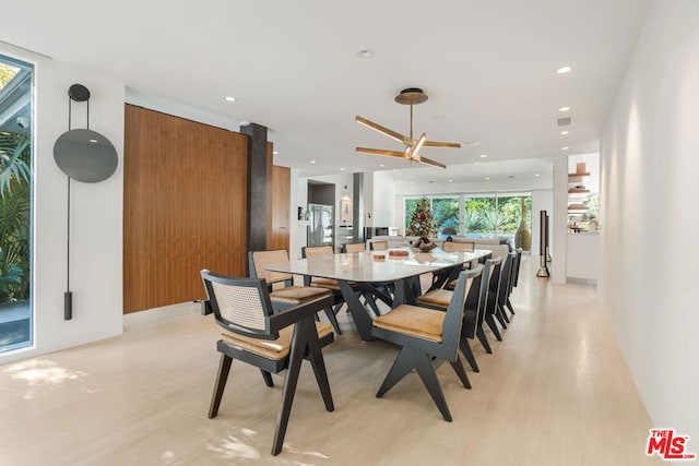 dining room featuring ceiling fan, a wall of windows, and light wood-type flooring