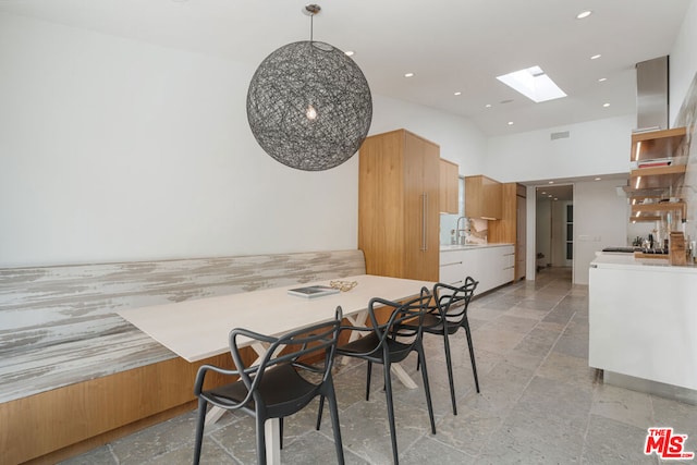 dining space featuring a high ceiling, sink, and a skylight