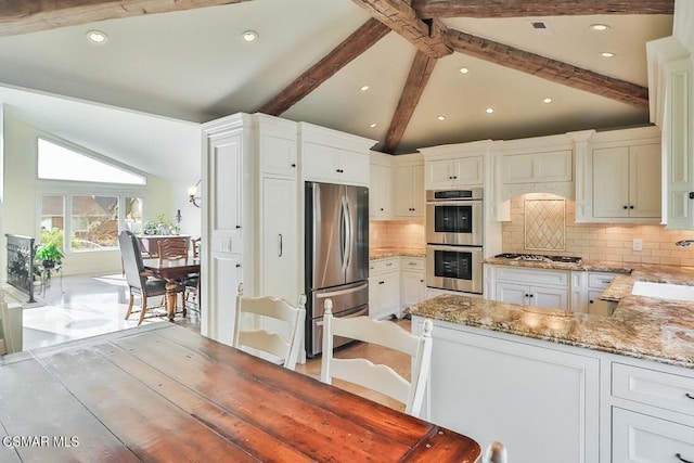 kitchen with decorative backsplash, light stone countertops, stainless steel appliances, and vaulted ceiling with beams