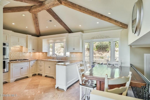 kitchen with decorative backsplash, sink, white cabinetry, and stainless steel appliances