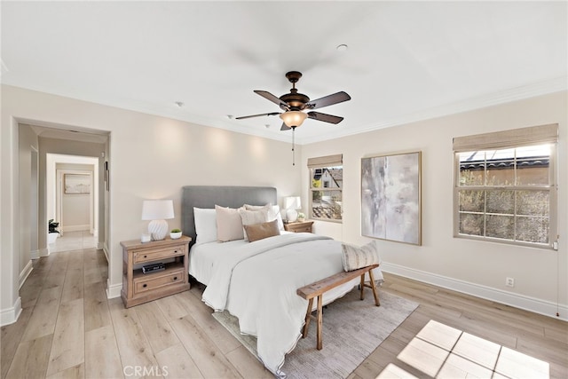 bedroom featuring ceiling fan, light hardwood / wood-style floors, multiple windows, and ornamental molding