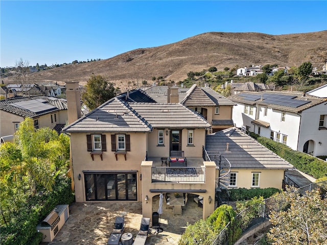 back of property with a mountain view and a balcony