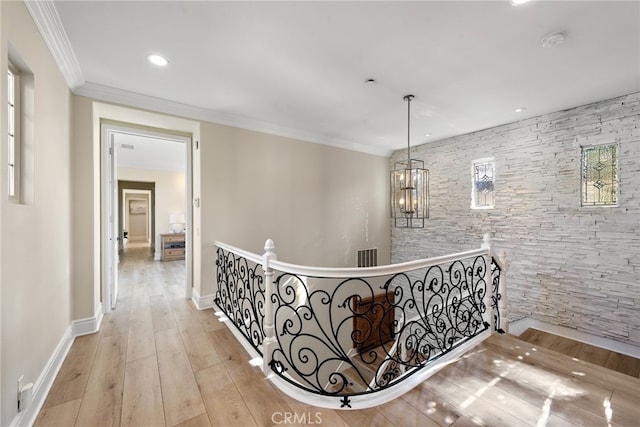 corridor featuring crown molding, a chandelier, and light hardwood / wood-style flooring