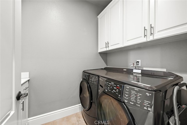 washroom featuring cabinets, light tile patterned floors, and washing machine and clothes dryer