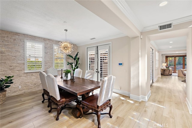 dining room featuring crown molding, light wood-type flooring, french doors, and an inviting chandelier