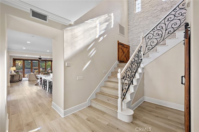 stairs featuring ceiling fan, crown molding, and hardwood / wood-style flooring