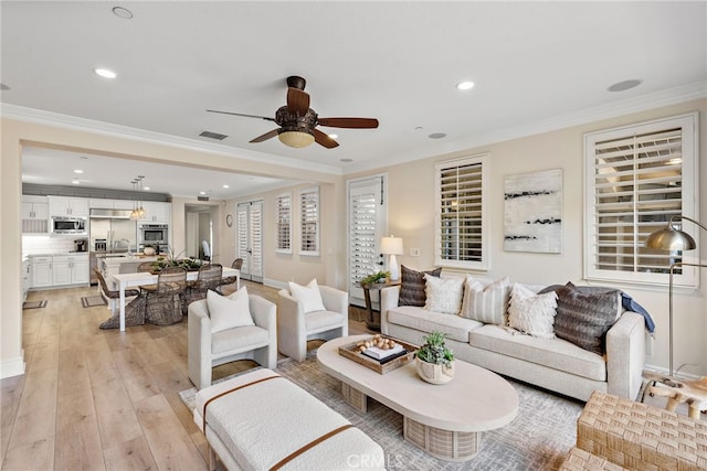 living room with light hardwood / wood-style floors, crown molding, and ceiling fan