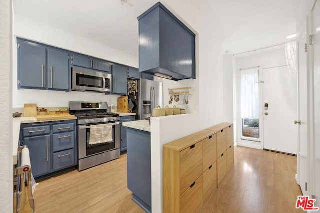 kitchen with light wood-type flooring, kitchen peninsula, stainless steel appliances, and blue cabinetry