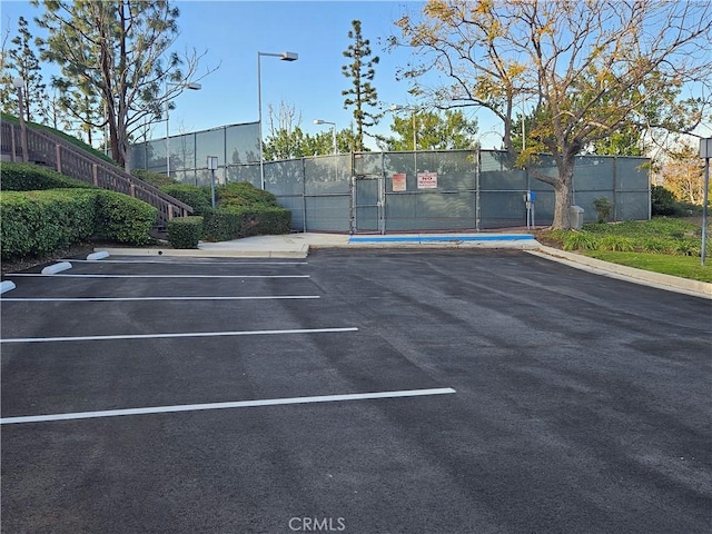 uncovered parking lot featuring fence and a gate