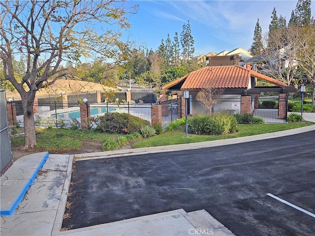 view of property's community with a pool, uncovered parking, and fence