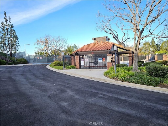 view of street featuring street lights, curbs, a gated entry, and a gate