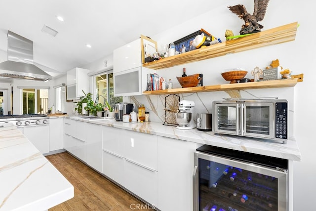 kitchen featuring light stone counters, beverage cooler, island range hood, and open shelves