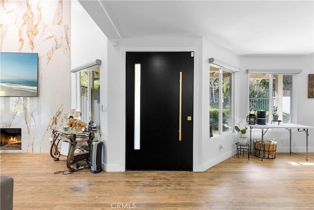 entryway featuring light wood-type flooring, a fireplace, and baseboards