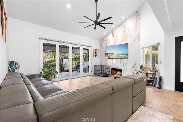 living room with recessed lighting, light wood-style flooring, a high end fireplace, ceiling fan, and high vaulted ceiling