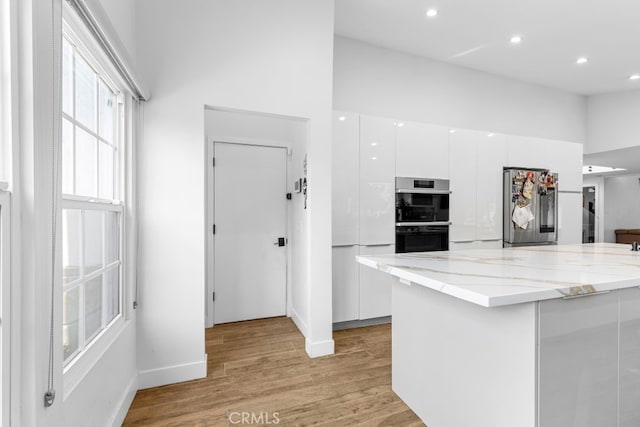 kitchen with smart refrigerator, white cabinets, modern cabinets, light stone counters, and double oven