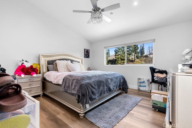 bedroom with ceiling fan, vaulted ceiling, and wood finished floors