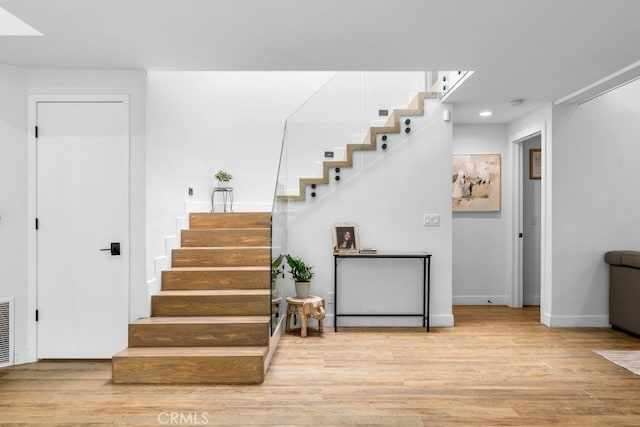 stairway featuring wood finished floors, visible vents, and baseboards