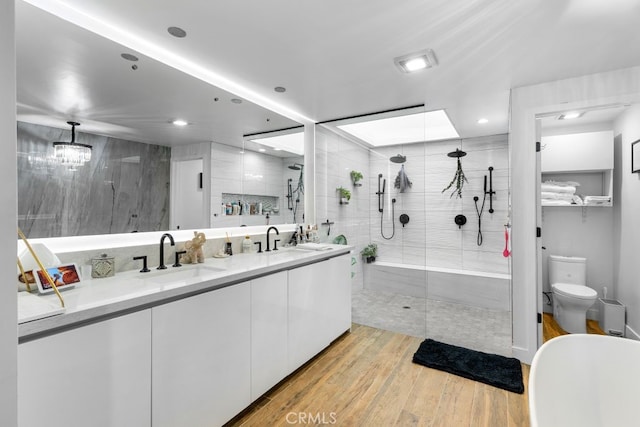 full bath with a stall shower, double vanity, a sink, and wood finished floors