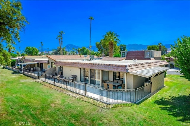 rear view of house with a patio area, a lawn, and a mountain view