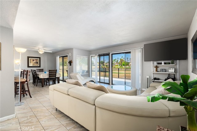 living room with ceiling fan and a textured ceiling