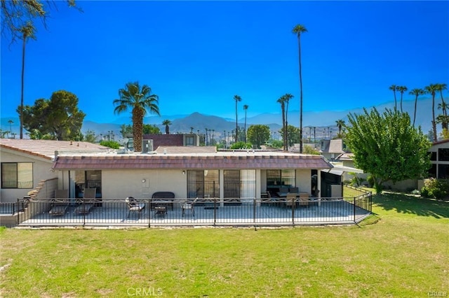 back of property with a mountain view, a yard, and a patio