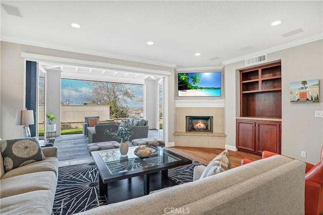 living room with crown molding, wood-type flooring, and built in features