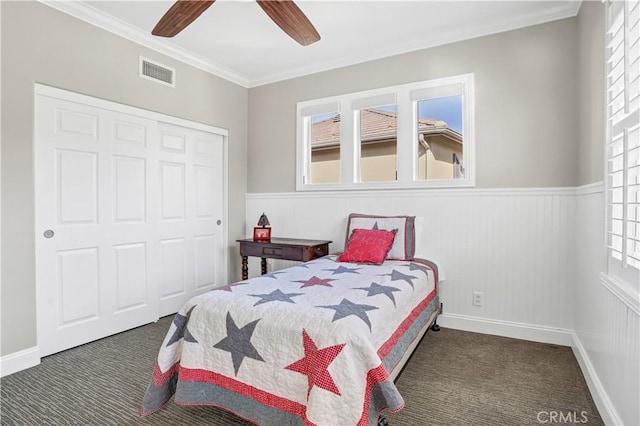 bedroom featuring ceiling fan, ornamental molding, dark carpet, and a closet