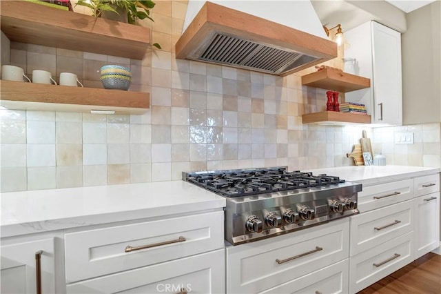 kitchen with decorative backsplash, custom exhaust hood, stainless steel gas cooktop, and white cabinets