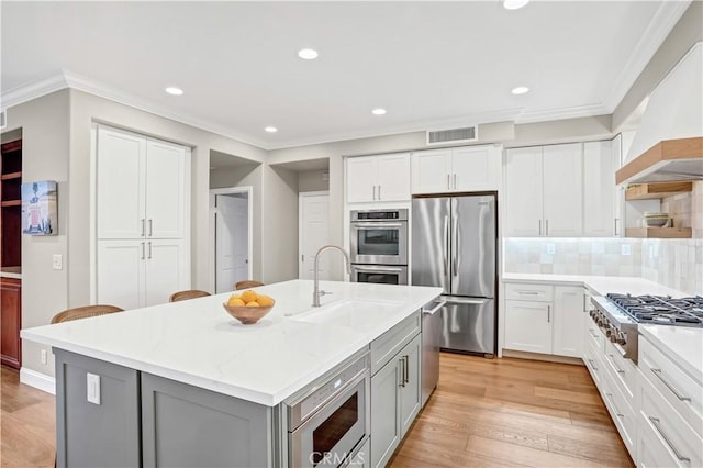 kitchen featuring sink, custom exhaust hood, a center island with sink, gray cabinets, and stainless steel appliances