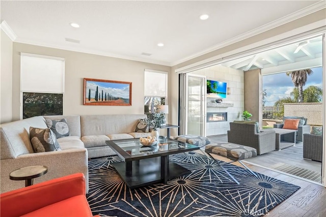 living room with a tile fireplace, ornamental molding, and hardwood / wood-style floors