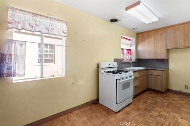 kitchen featuring tasteful backsplash, light parquet flooring, sink, and white gas range