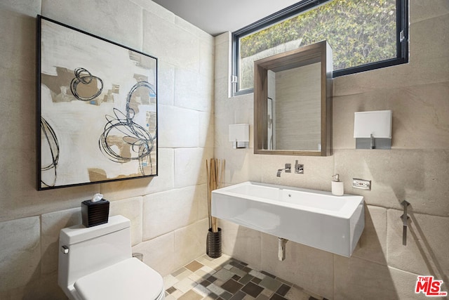 bathroom with toilet, tile walls, and a wealth of natural light