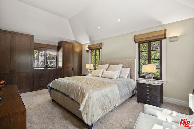 bedroom featuring multiple windows, vaulted ceiling, and light carpet