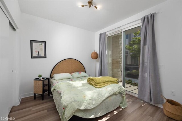 bedroom with dark wood-type flooring, a closet, and access to outside