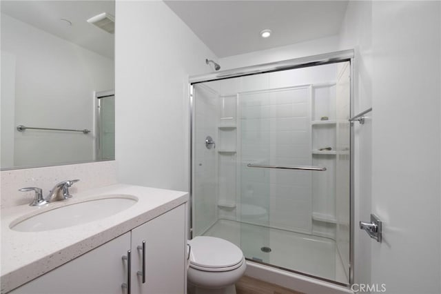 bathroom with a shower with shower door, toilet, and vanity