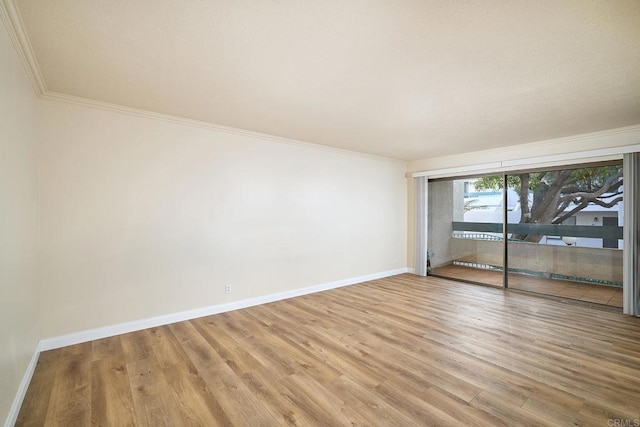 empty room featuring crown molding, wood finished floors, and baseboards