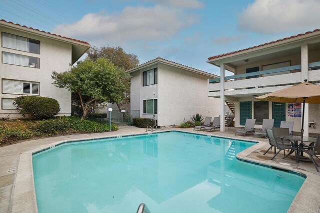 pool with a patio area, fence, and stairway